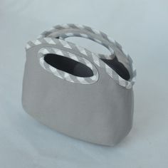 a gray bag with two handles is sitting on a white tablecloth and has grey trim around the edges