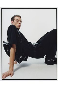 a man laying on the ground with his legs spread out and wearing black clothing,