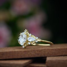 a gold ring with three pear shaped diamonds on it, sitting on a wooden surface