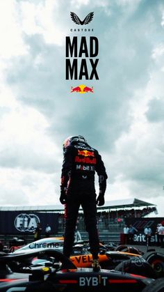 a man standing on top of a red bull racing car in front of a cloudy sky