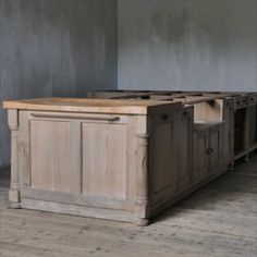 a kitchen island made out of wood in a room with gray walls and wooden floors