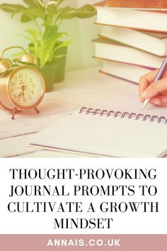 a person writing on a notepad next to a pile of books and an alarm clock