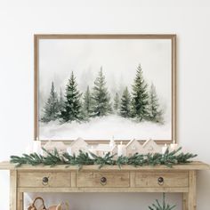 a christmas mantle with candles, pine trees and evergreen branches on it in front of a painting