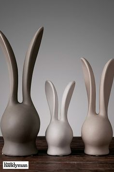 three white vases sitting on top of a wooden table next to eachother