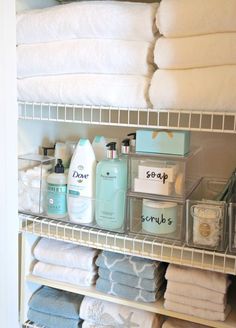 the shelves in this bathroom are organized with clear bins and containers for personal care items