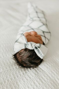 a baby laying on top of a bed wearing a bow