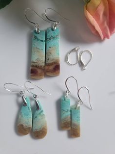 These are handmade pairs of blue dangle Opalized Wood earrings. The drop from earlobe is an inch and a half to 2 inches. The colors include turquoise blue with sage green and amber. The bales and hooks are Sterling Silver. Both fishhooks and leverbacks are available. Multicolor Wooden Beads Dangle Earrings, Turquoise Patina Drop Earrings, Unique Turquoise Patina Earrings, Opalized Wood, Turquoise Dangle Earrings With Ocean-inspired Style, Nature-inspired Turquoise Dangle Earrings, Bleu Turquoise, Wood Earrings, Fish Hook