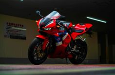 a red motorcycle parked in a garage with its front wheel still attached to the bike