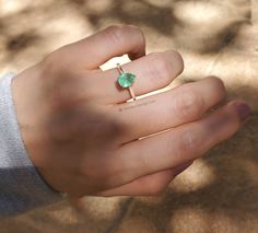 a person's hand holding a ring with a green stone on it and a cross in the middle