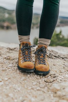 the legs and feet of a person wearing hiking boots on top of a rocky surface