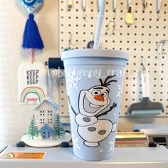 a cup with a straw in the shape of a snowman is sitting on a counter