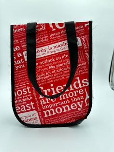 a red and black bag with words all over it, sitting on a white surface