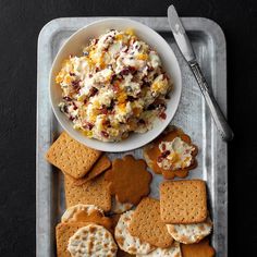 a plate with crackers, crackers and cheese on it next to a bowl of dip