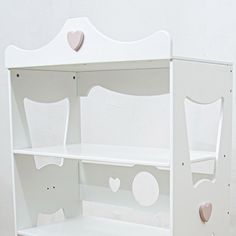 a white book shelf with hearts on the top and bottom shelves, against a white wall