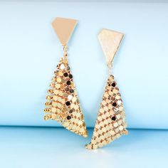 These geometric gold plated earrings will add instant sparkle and shine to any outfit. The handkerchief-inspired dangle design creates movement when you walk, catching the light in a unique way. The triangle stud backs ensure they'll stay put all night long, through dancing, laughing and all the festivities. Perfect party earrings for fashion-forward gals seeking a statement accessory that stands out from the crowd. Materials: 24k gold plated brassDimensions: 2.61 x 0.92 in Jewelry Care: See more information about how to care for your jewelry here. Shipping Policy: Orders will be shipped within 1-3 business days. Economy shipping will take 7-14 days to arrive and standard shipping is 1- 4 days for U.S. orders. International shipping time is depended on the country and per shipping method. Trendy Gold Triangle Earrings, Triangle Gold Metal Earrings, Gold Triangle Metal Earrings, Gold Geometric Earrings For Party, Geometric Gold Earrings For Party, Chic Geometric Earrings For Party, Gold Geometric Jewelry For Party, Trendy Gold Chandelier Earrings For Evening, Diamond-shaped Gold Jewelry For Party