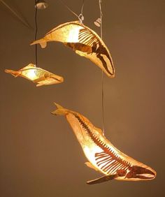 three light fixtures hanging from strings in the shape of fish