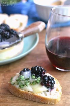 a piece of bread with berries on it next to a glass of wine