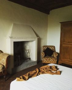 a bedroom with a bed, chair and fire place in it next to a dresser