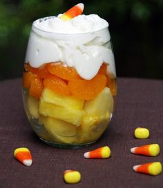 candy corn fruit parfait in a glass jar with marshmallows on the side