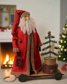 a santa figurine standing next to a christmas tree on top of a wooden box