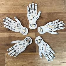 five white gloves with eyeballs on them are arranged in a circle and placed on a wooden floor