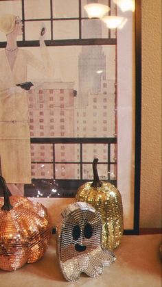 three decorative pumpkins sitting on top of a table in front of a large window