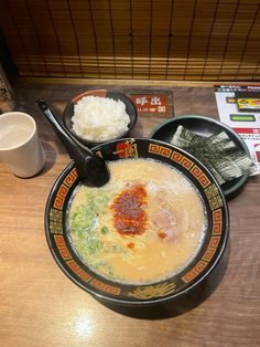 a bowl of soup with chopsticks and rice on a table in a restaurant