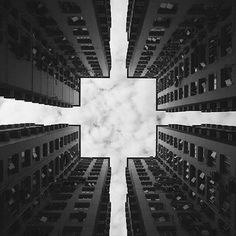 looking up at tall buildings from the ground in black and white with a sky background