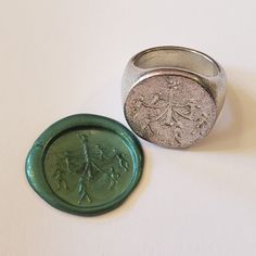 a wax stamp and ring sitting next to each other on a white surface with a green seal in front of it