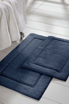 two blue bath mats on the floor in a bathroom