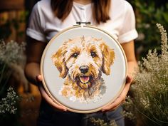 a woman holding a cross stitch dog in her hands