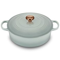 a white casserole with a copper knob on the top and bottom, sitting in front of a white background