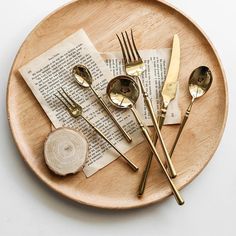 a plate topped with forks and spoons next to an open book