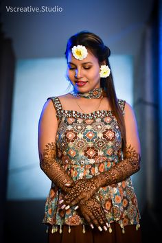 a woman with henna and flower in her hair is smiling at the camera while she stands