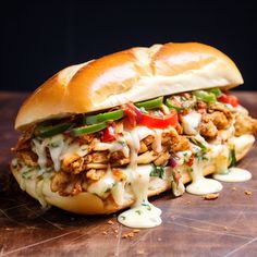 two sandwiches with meat, cheese and vegetables on a cutting board