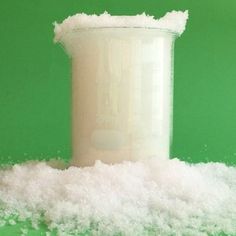 a container filled with sugar sitting on top of a pile of white foam next to a green wall