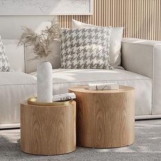 two wooden stools sitting next to each other in front of a white couch with pillows on it