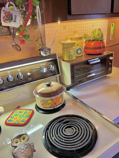 a stove top oven sitting inside of a kitchen next to a counter with pots and pans on it