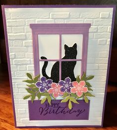 a card with a black cat sitting in a window sill and flowers on it