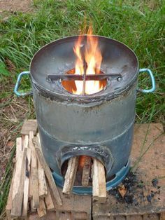 a large metal pot sitting on top of a pile of wood next to a fire