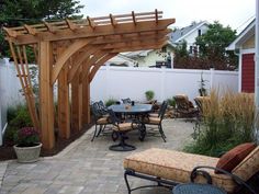 an outdoor dining area with table, chairs and arbor - style pergolated structure