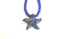 "This is a one-of-a-kind royal blue art glass lampwork starfish pendant necklace.  The necklace is about 21\" long and the starfish pendant hangs down another 2\".  The pendant is made up of metallic swirls of blue, green gold and copper.  The body of the necklace is made up of faceted royal blue glass beads.  The clasp is a silver plated lobster claw.   The necklace is strung on wire for durability and strength and will be shipped in a jewelry box which is perfect for gift giving or storage.  L Blue Green Gold, Necklace Art, Glass Lampwork, Starfish Pendant, Starfish Necklace, Blue Art, Green Gold, Glass Bead, Blue Glass