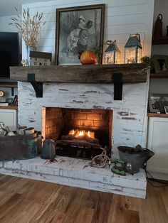 a fire place in the middle of a room with pictures on the wall and wood flooring