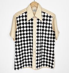 Vintage 70s button-up shirt that has been renewed with added cotton checkerboard printed fabric. Original shirt is 65% polyester 35% cotton. Marked size M, please check measurements to ensure fit. FREE DOMESTIC SHIPPING! Measurements taken flat across shirt: Bust: 22" Length: 26.5" Sleeve: 8.5" Shoulder to shoulder: 17.75" all sales final Retro Gingham Tops With Button Closure, Retro Gingham Top With Button Closure, Retro Plaid Collared Tops, Cotton Collared Top With Houndstooth Pattern, Retro White Button-up Camp Shirt, Vintage Plaid Tops With Graphic Print, Retro Short Sleeve Plaid Shirt, Retro Plaid Short Sleeve Shirt, Retro Plaid Top With Graphic Print