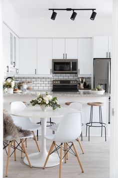 a kitchen with white cabinets and an island in the middle, surrounded by stools