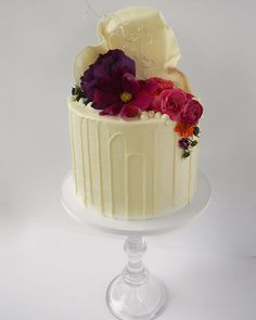 a white cake with purple and red flowers on top