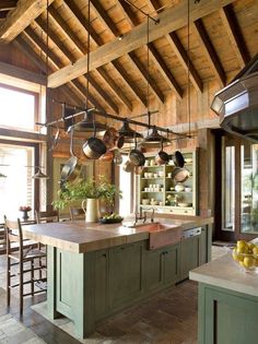 a large kitchen with lots of pots and pans hanging from the ceiling over the island