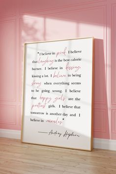 a pink room with a framed quote on the wall and hardwood flooring in front of it