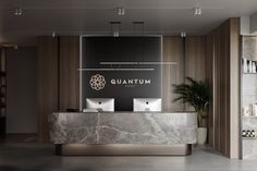 the front desk of an office with marble counter tops and gold lettering that reads quantum