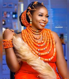 a woman in an orange dress with beads on her neck and necklaces around her neck